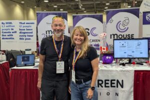 Tim Bussey and Lisa Saksida in front of the Touchscreen Cognition booth at AAIC2025